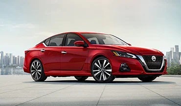 2023 Nissan Altima in red with city in background illustrating last year's 2022 model in Vann York's High Point Nissan in High Point NC